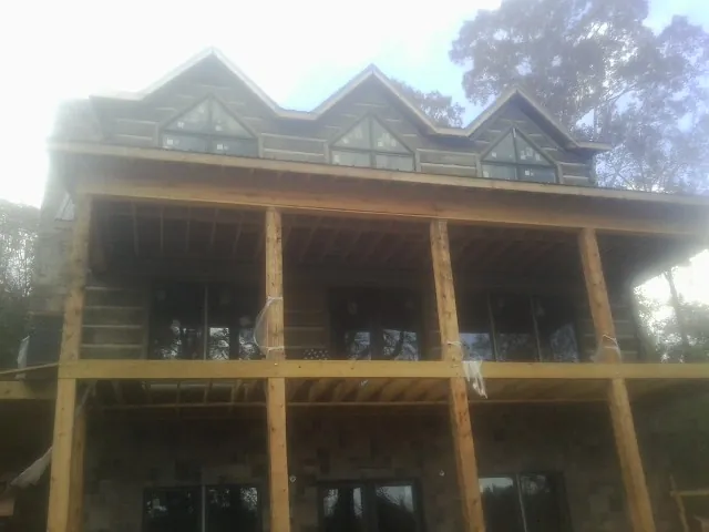 Dormers and porch framing on a large log home under construction — Roof Coating work by our crew in West Edmeston