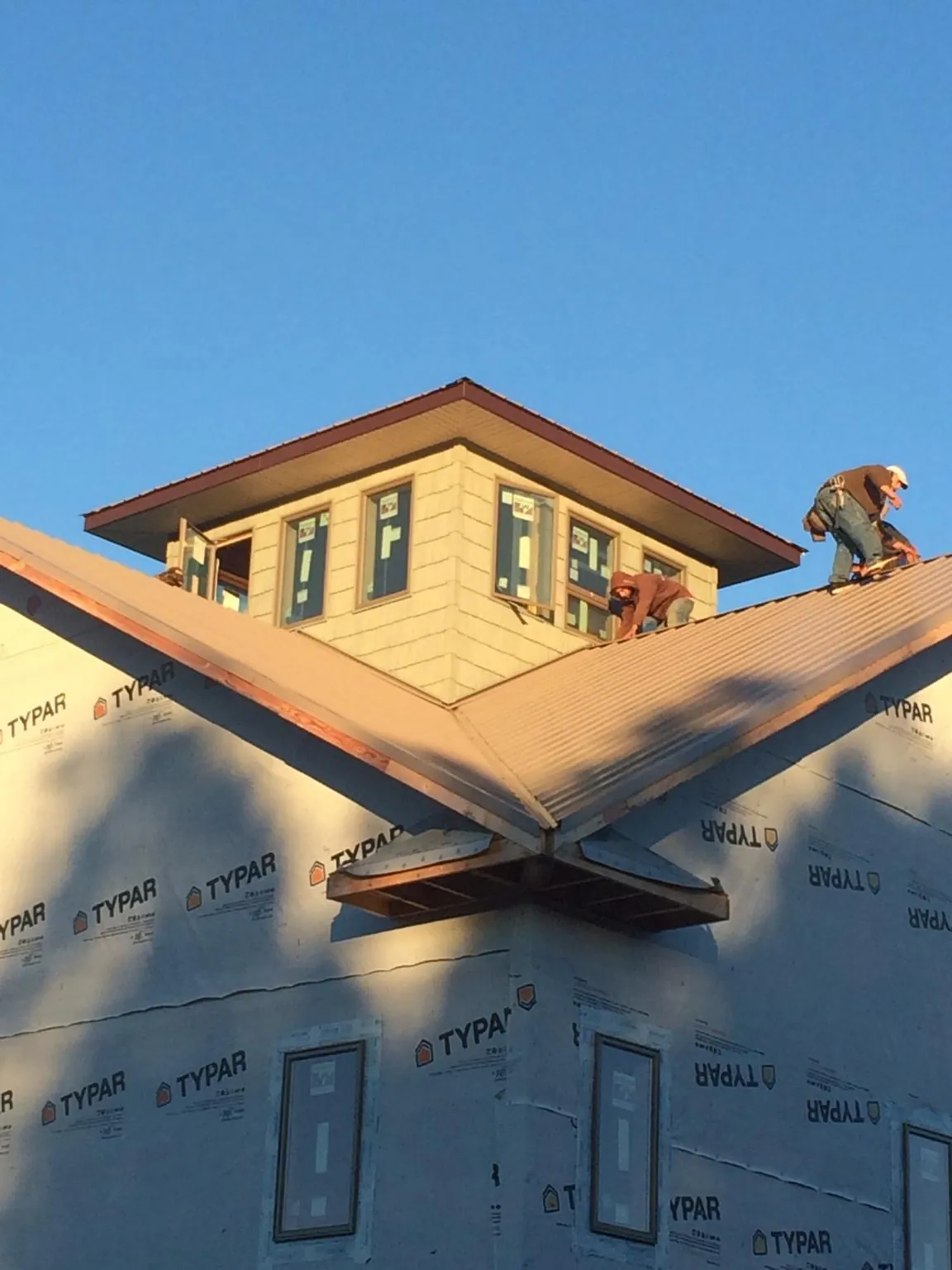 Roofers working around a rooftop cupola on a new metal roof at sunset — Roof Waterproofing in West Edmeston by Roofing Brothers